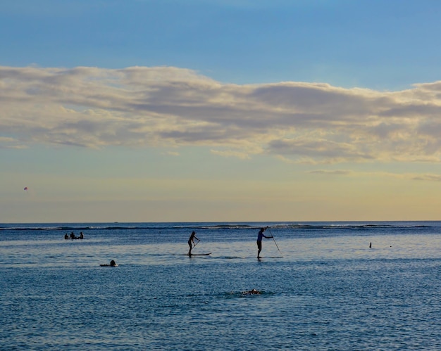 Foto silueta de personas en el mar contra el cielo durante la puesta de sol