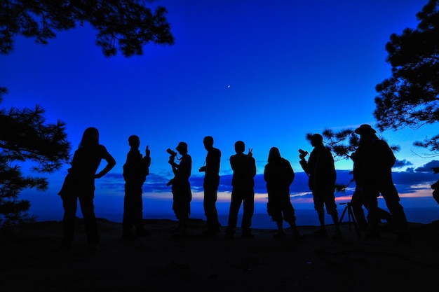 Silueta de personas de pie en el campo contra el cielo azul