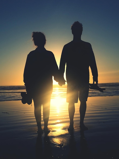 Foto silueta de personas en la playa al atardecer