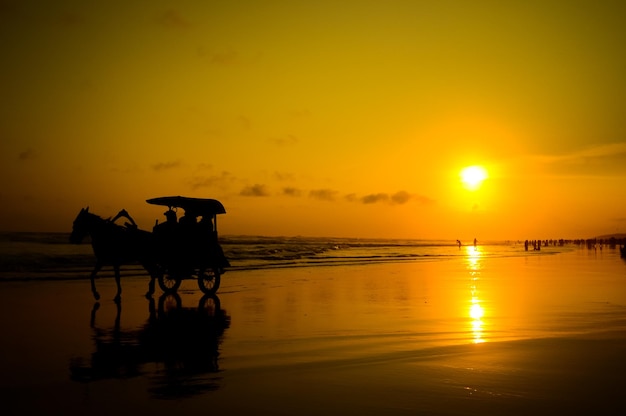 Foto silueta de personas en la playa contra el cielo durante la puesta de sol