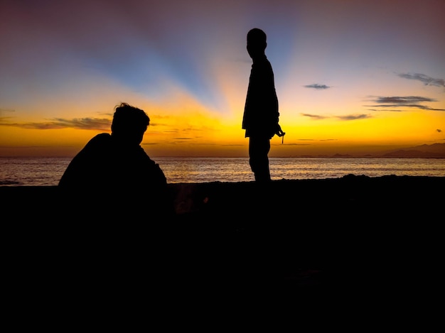 silueta de personas con salida del sol en la playa