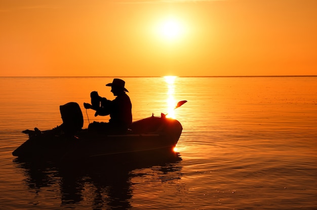 Foto silueta de pescador en el barco en la luz del sol de la mañana