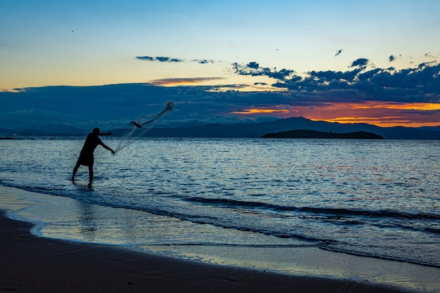 Silueta de un pescador lanzando la red de pesca