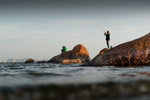 La silueta del pescador en la roca en el mar.
