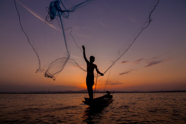 Silueta de pescador tirando red en el lago