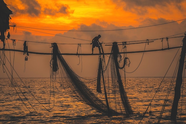 Foto silueta de pescadores lanzando redes en cañas de pescar al amanecer los pescadores tradicionales preparan la red de pesca que la gente local llama day hang khoi concepto de pesca y vida cotidiana