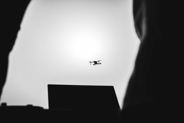 Silueta de piloto de drones volando con quadcopter al aire libre al atardecer Piloto de drones volando y comandando desde base aérea Tecnología y concepto de espionaje