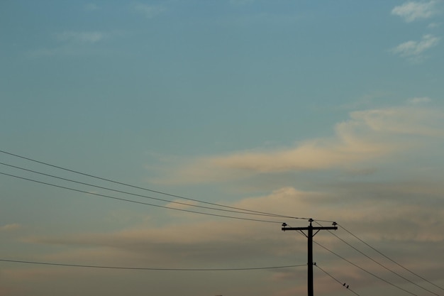 Silueta de un poste eléctrico contra el cielo durante la puesta de sol