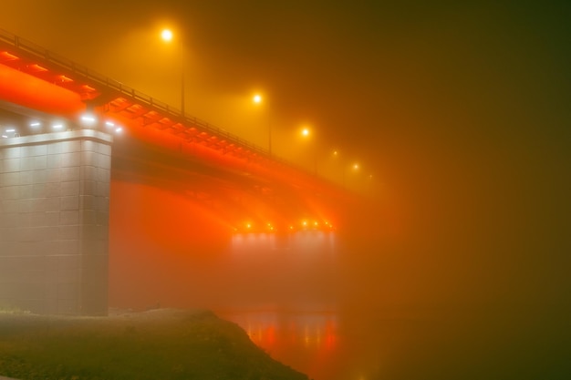 Silueta de puente iluminada a través de la niebla por la noche