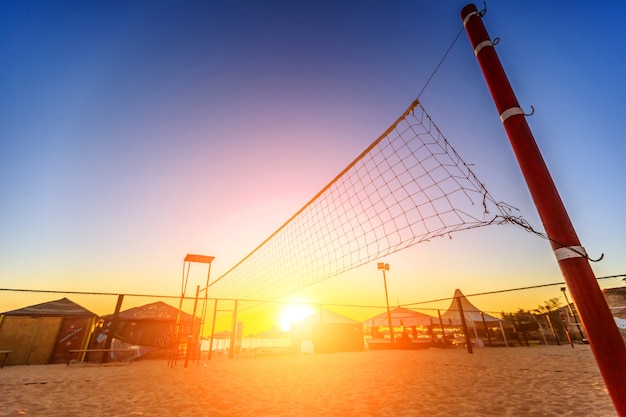 Silueta de una red de voleibol y amanecer en la playa