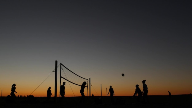 Silueta de red de voleibol en la cancha de playa al atardecer jugadores en la costa de california