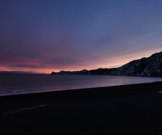 Silueta de una región montañosa con la luz del sol detrás vista al otro lado de un lago