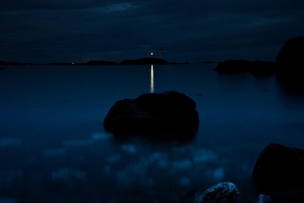 Foto la silueta de las rocas por el mar contra el cielo al anochecer