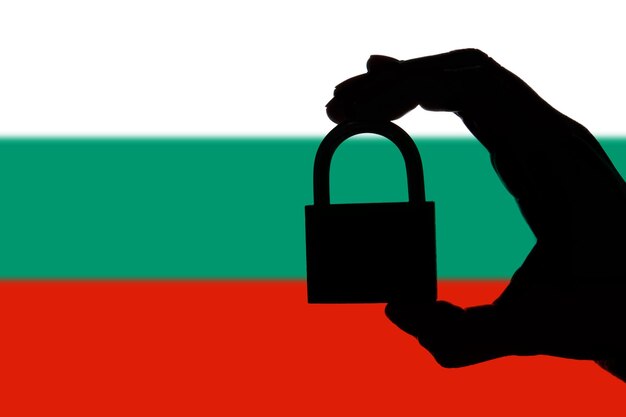 Silueta de seguridad de Bulgaria de la mano que sostiene un candado sobre la bandera nacional