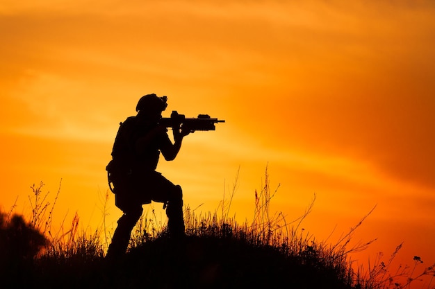 Foto silueta de soldado u oficial militar con armas al atardecer