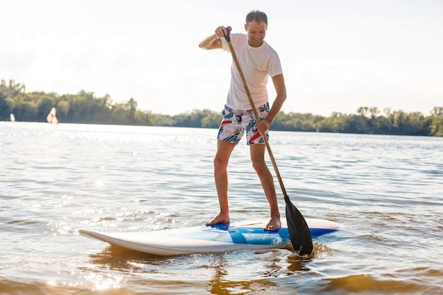 Silueta de stand up paddle boarder remando al atardecer