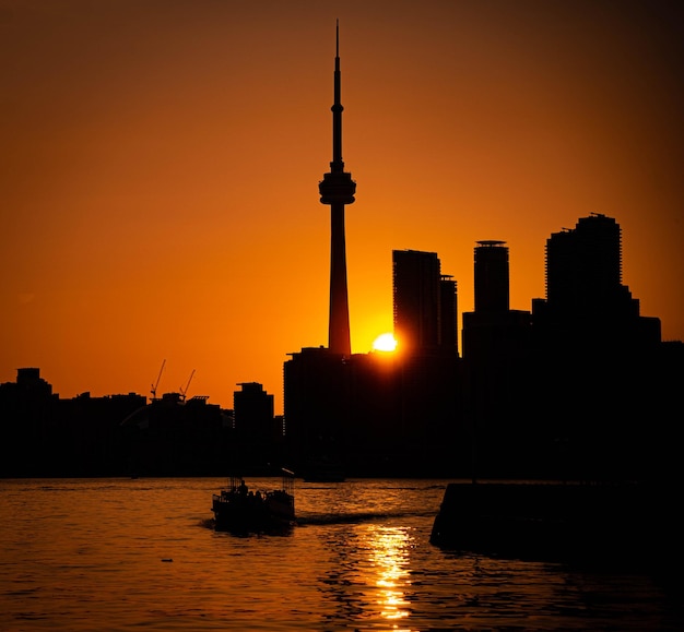 Silueta de la Torre CN rodeada de agua y edificios durante una hermosa puesta de sol en Toronto