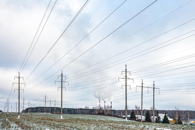 Silueta de las torres de pilones eléctricos de alto voltaje en el fondo de hermosas nubes humeantes tuberías de una planta de energía térmica