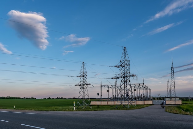 Silueta de las torres de pilones eléctricos de alto voltaje en el fondo de hermosas nubes nocturnas