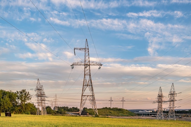 Silueta de las torres de pilones eléctricos de alto voltaje en el fondo de hermosas nubes nocturnas