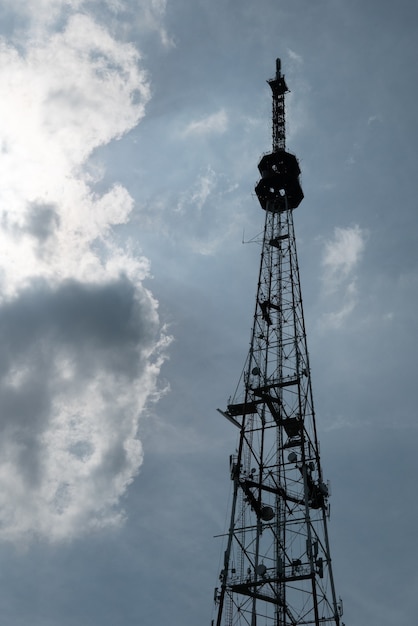 Silueta de torres de transmisión y comunicación de señal de TV con el telón de fondo de un cielo nublado