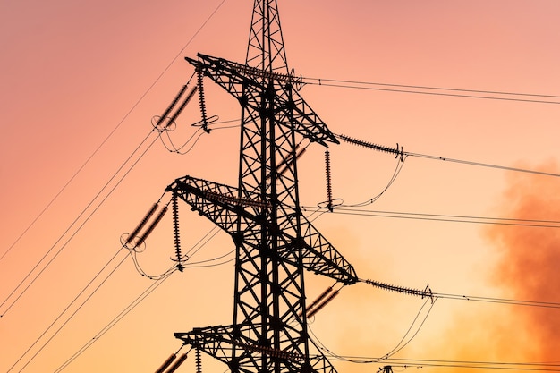 Silueta de torres de transmisión eléctrica Sombra de torre de alto voltaje en puesta de sol de color naranja