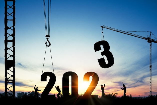 Silueta de trabajador de la construcción con grúa y cielo nublado para la preparación de la fiesta de bienvenida de año nuevo 2023 y cambiar nuevos negocios.