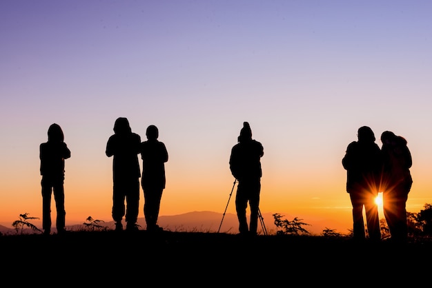 Una silueta de un turista de pie en un amanecer de montaña fotografiando en Mae Hong Son, Tailandia.