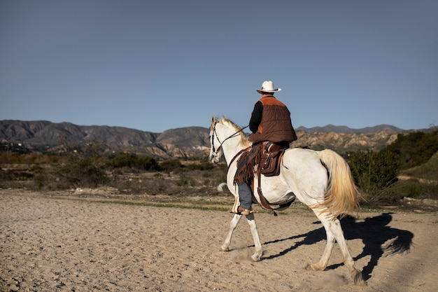 Silueta de vaquero con caballo contra luz cálida