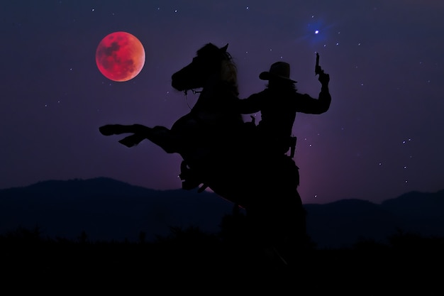 Foto la silueta del vaquero a caballo con luna de sangre