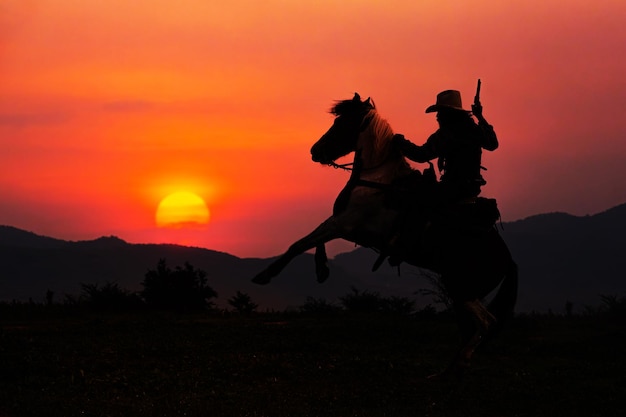 Silueta de vaquero a caballo y puesta de sol como fondo