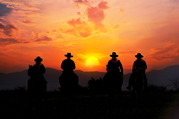 Foto silueta de vaquero a caballo con vista a la montaña y cielo al atardecer.