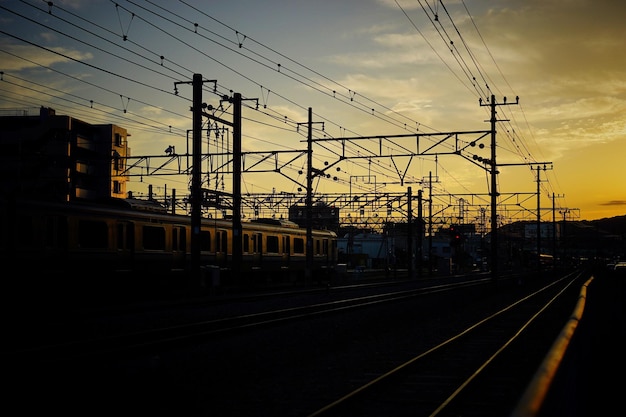 La silueta de las vías del ferrocarril contra el cielo durante la puesta de sol