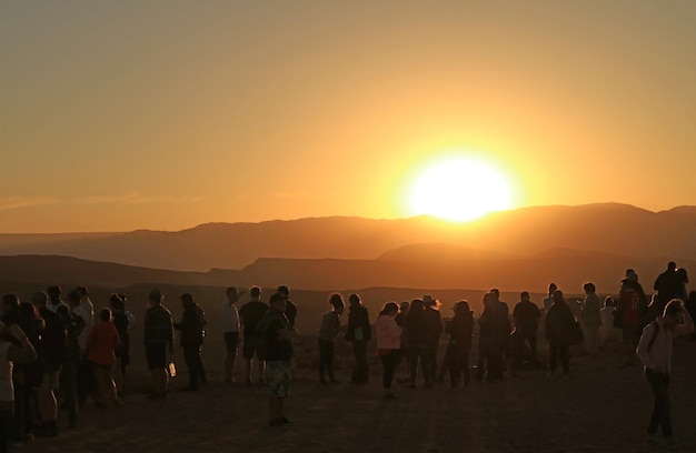 Silueta de visitantes en el acantilado viendo la puesta de sol en el Valle de la Luna en el desierto de Atacama, Chile