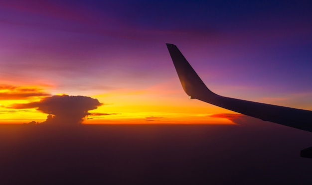 Silueta de vista de ala de avión fuera de la ventana el fondo del cielo nublado atardecer