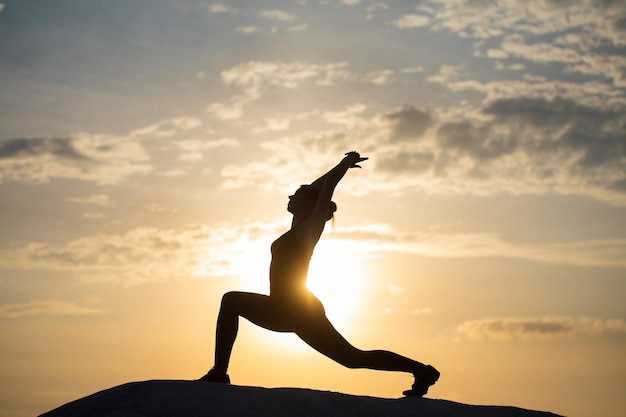 Silueta de yoga Chica de meditación en el fondo del mar durante la puesta de sol Fitness y estilo de vida saludable