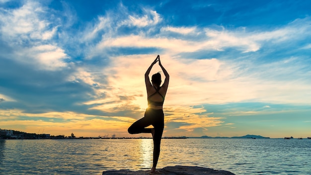 Silueta de yoga Mujer de meditación en el océano durante la increíble puesta de sol.