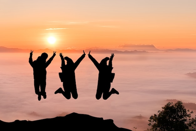 Siluetas de amigos en el pico de la montaña. Deporte y concepto de vida activa