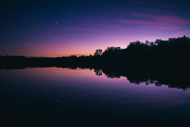 Foto siluetas de árboles junto al lago contra el cielo durante la puesta de sol