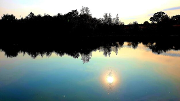 Foto siluetas de árboles junto al lago contra el cielo durante la puesta de sol