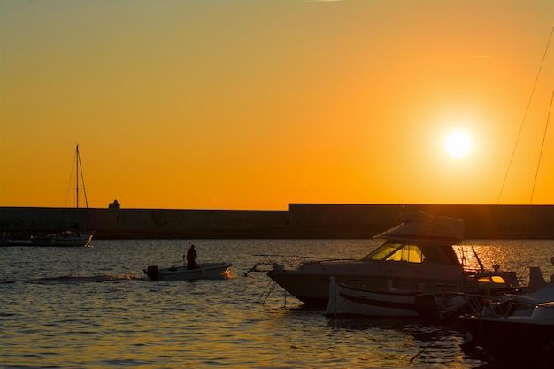 Siluetas de barcos en el puerto de Alghero al atardecer