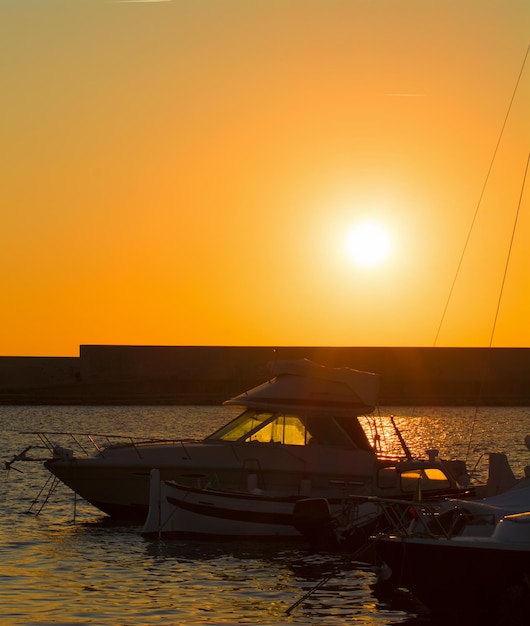 Siluetas de barcos en el puerto de Alghero al atardecer