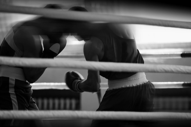 Siluetas en blanco y negro de atletas de boxeo en el ring Deportes de combate Poca profundidad de campo centrada en las manos de los atletas
