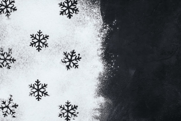 Foto siluetas de copos de nieve hechos de harina en un espacio de copia en negro.
