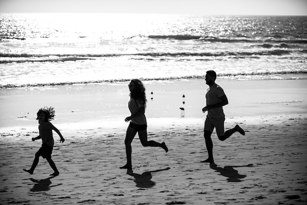 Siluetas de familia trotando a lo largo de la playa del mar al amanecer siluetas de entrenamiento al aire libre de corredores spor
