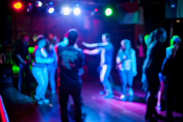 Siluetas de gente bailando en un club frente a brillantes luces escénicas concepto de vida nocturna