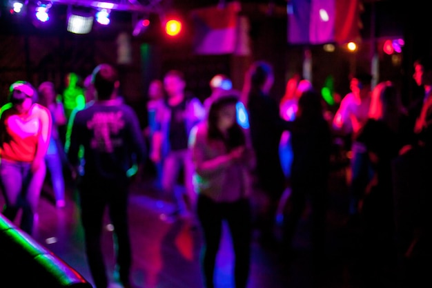 Siluetas de gente bailando en un club frente a brillantes luces escénicas concepto de vida nocturna