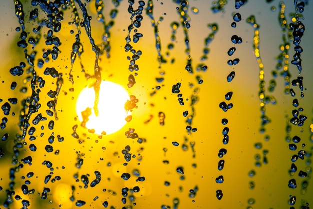 Foto siluetas de gotas que caen fuente de agua con el telón de fondo de la puesta de sol