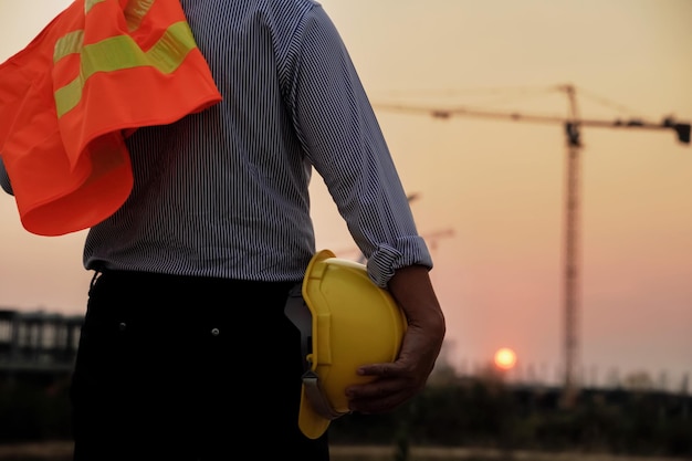 Siluetas de ingenieros y trabajadores que trabajan en un sitio de proyecto inmobiliario en un edificio industrial Preparándose para terminar el trabajo por la noche