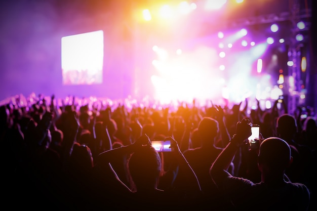 Foto siluetas de multitud de conciertos frente a las luces del escenario brillante.